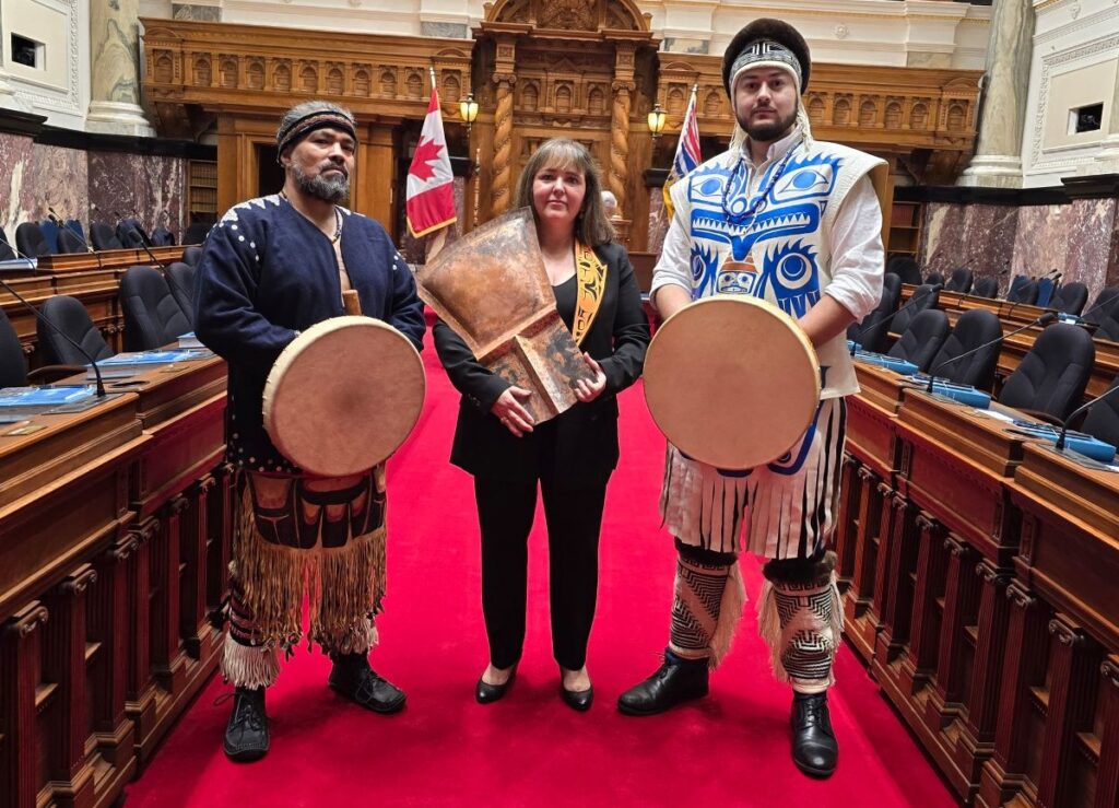 Laanas stands between Haida Drummers Donnie Edenshaw (left) and Cohen Bradley (right), her son-in-law. Image: Kevin Light.